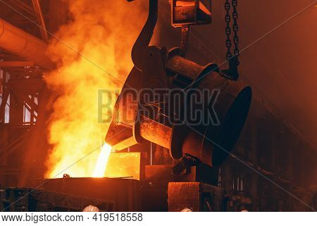 Molten Metal Pour From Big Container Into Sand Mold With Sparks. Iron Casting In Metallurgy Foundry 