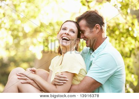 Young Couple In Walking Clothes Resting On Tree In Park