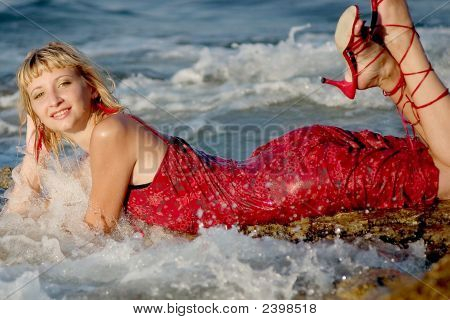 Vrouw In rode jurk liggend op golven