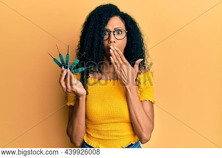 Middle age african american woman holding picklock to unlock security door covering mouth with hand, shocked and afraid for mistake. surprised expression 