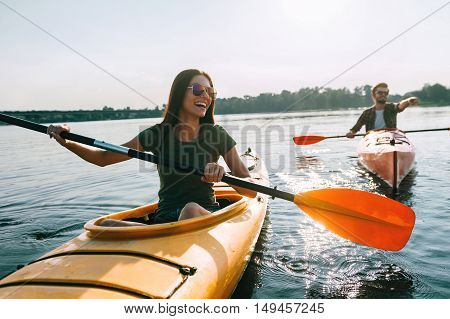 Couple kayaking together. Beautiful young couple kayaking on lake together and smiling