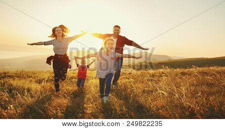 Happy Family: Mother, Father, Children Son And  Daughter On Nature  On Sunset