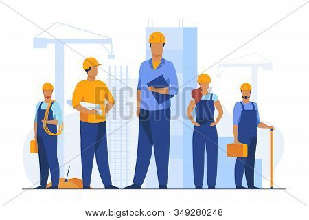 Construction Team Working On Site. Builders, Engineers, Architects In Helmets And Overalls Holding B