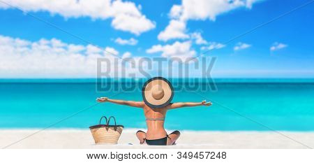 Beach caribbean travel vacation woman happy carefree with open arms on summer holiday panoramic banner. Tourist sun sunbathing bikini body skincare sun protection with hat enjoying summer holidays.