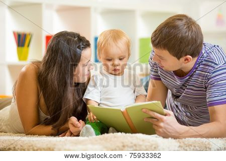 Young parents mom and dad reading children book to baby boy