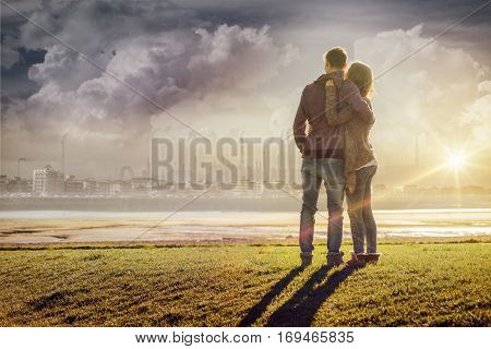 Happy romantic loving couple at the lake hugging and looking away love and relationships concept