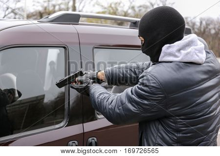 Male thief with pistol trying to steal car