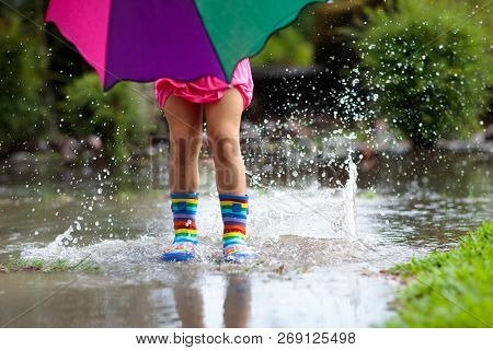 Kid With Umbrella Playing In Summer Rain.