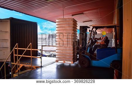 Forklift Stuffing-unstuffing Pallets Of Cargo To Container On Warehouse Leveler Dock.