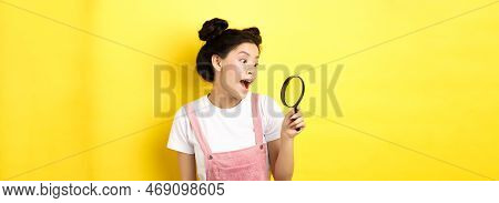 Excited Asian Girl Found Interesting Thing, Looking Through Magnifying Glass Amazed, Standing On Yel