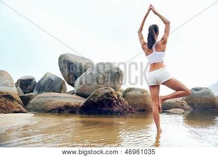 Yoga Strand Frau tun Pose am Meer für Zen-Gesundheit und ruhigen Lebensstil