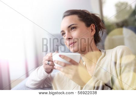 Peaceful woman relaxing at home with cup of tea