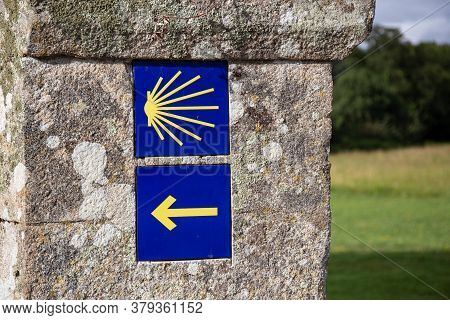 Camino De Santiago Yellow Scallop And Arrow Sign On Old Stone Wall. Way Of St. James Signs Pilgrimag