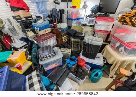 Hoarder room packed with storage boxes, old electronics, files, business equipment and household items.