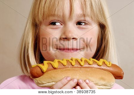 Little girl eating a hot dog.Kid eating hot dog.