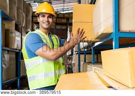 Indian warehouse worker put cardboard box in to shelf with muslim Islam asian worker do inventory in warehouse distribution center environment. Using in business warehouse and logistic concept.