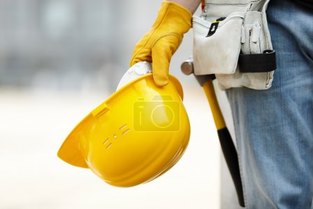 Foto de Constructor con casco amarillo y guantes de trabajo en obra - Imagen libre de derechos