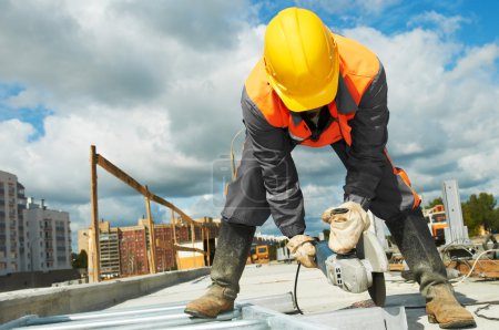 Foto de Constructor trabajador con amoladora máquina de corte de piezas metálicas en el sitio de construcción - Imagen libre de derechos