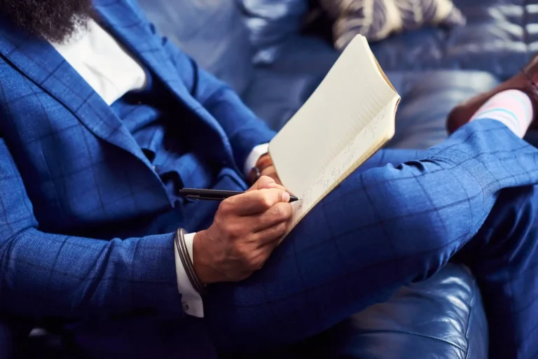 A man writing in a personal growth plan in a notebook