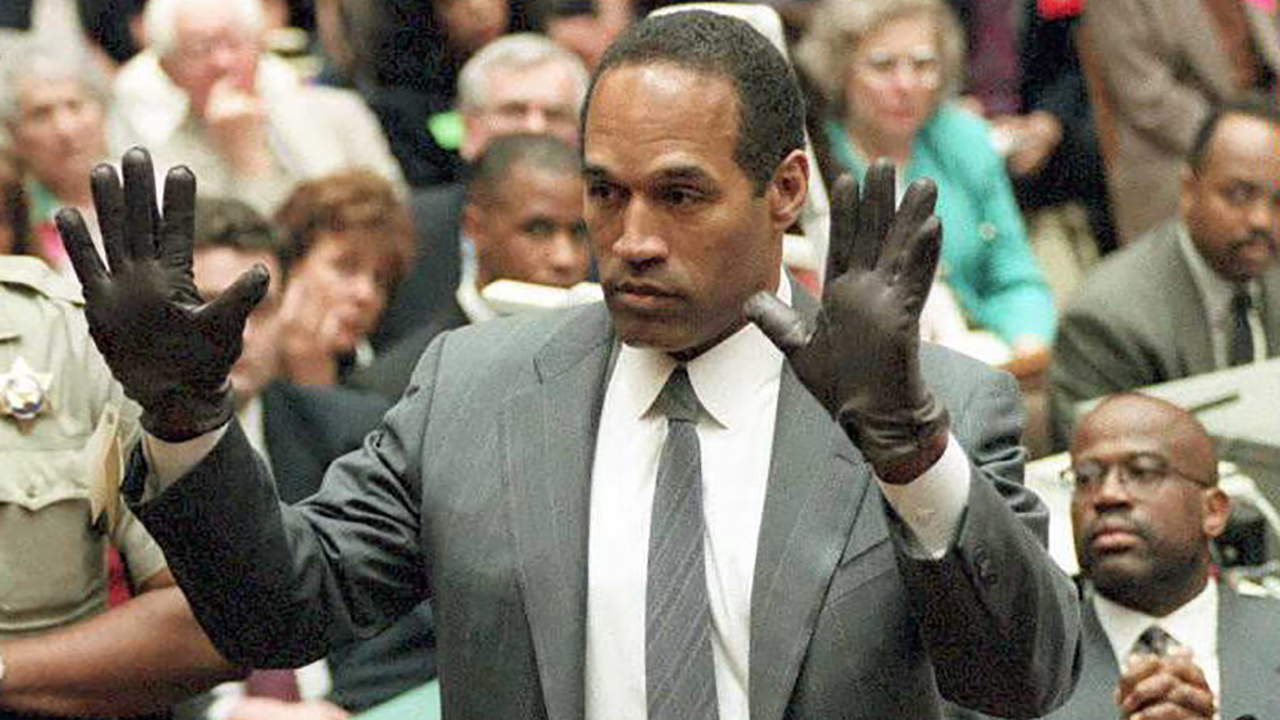 LOS ANGELES, CA - JUNE 21:  O.J. Simpson shows the jury a new pair of Aris extra-large gloves, similar to the gloves found at the Bundy and Rockingham crime scene 21 June during his double murder trial in Los Angeles. Depety Sheriff Roland Jex(L) and Prosector Christopher Darden(R) look on.