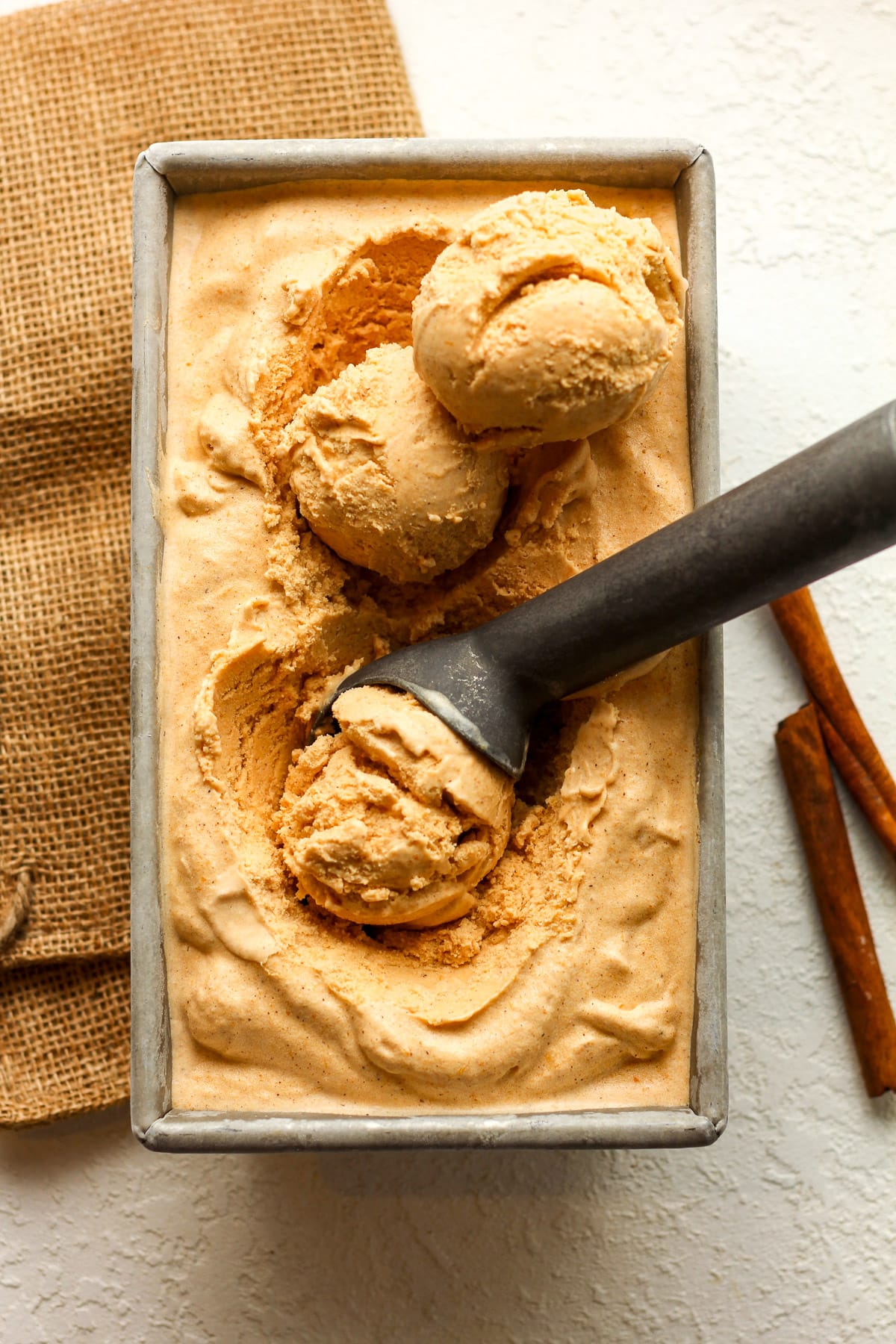 A pan of pumpkin ice cream with scoops inside.