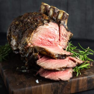 standing rib roast sliced on a wood cutting board