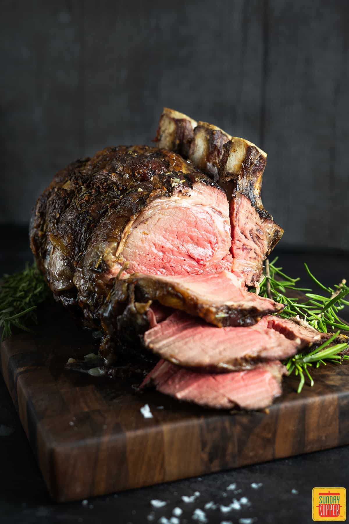 slices hanging off a standing rib roast on a wood board