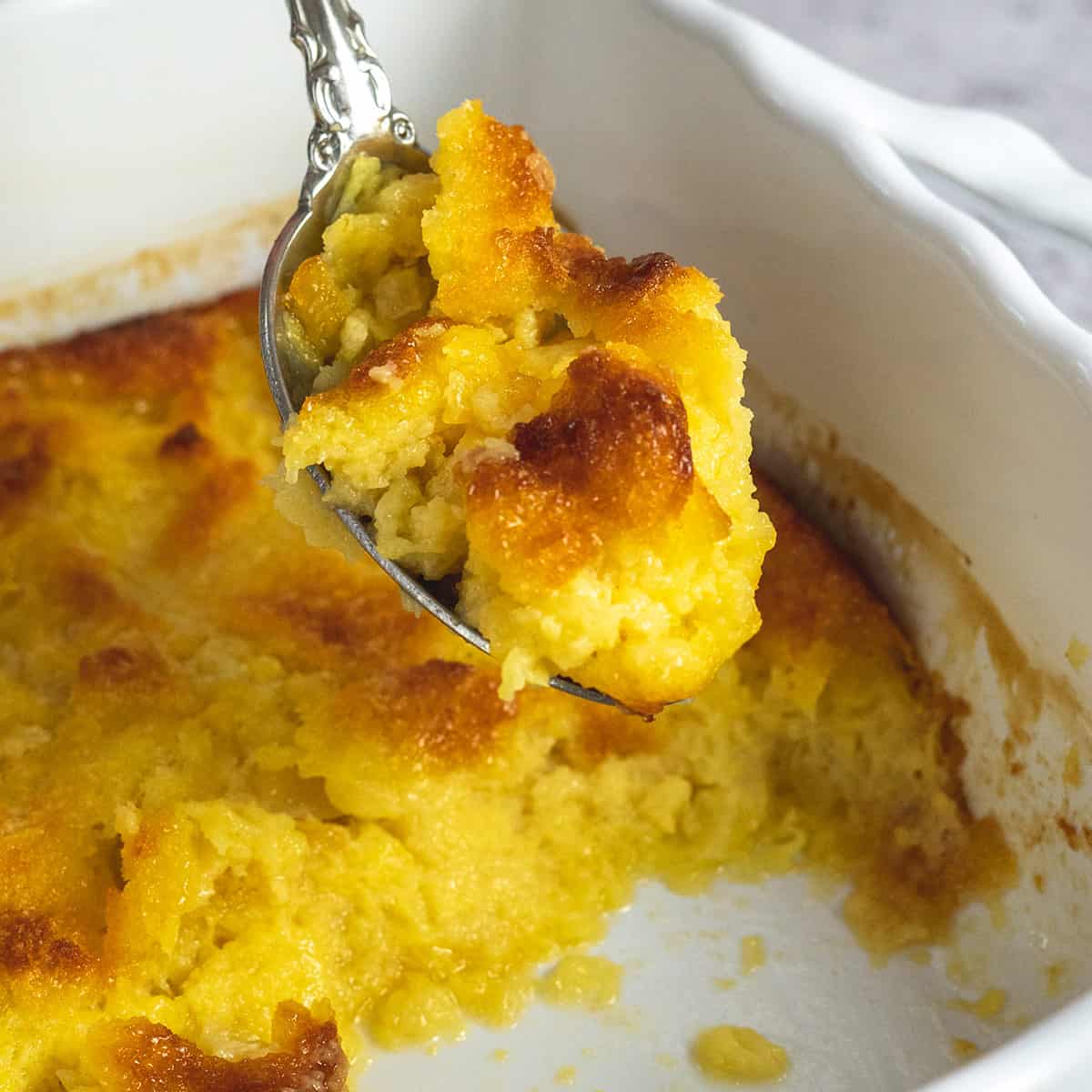 a closeup of a spoon full of pineapple casserole to show the texture