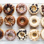 Donuts being decorated on a wire cooling rack.