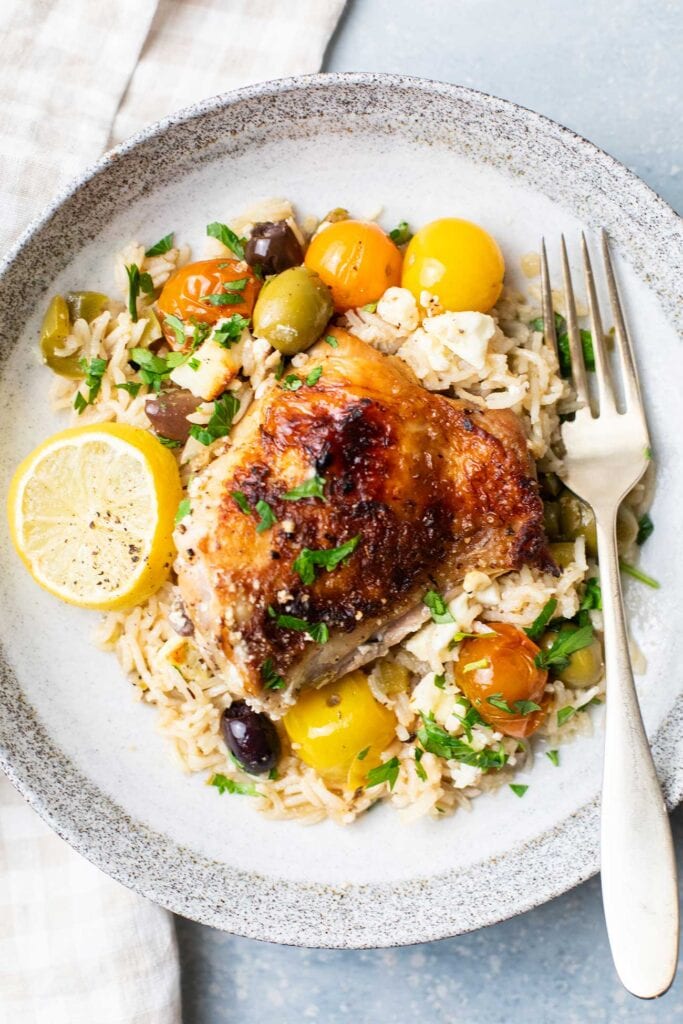 A plate with a serving of rice and vegetables topped with a browned chicken breast.