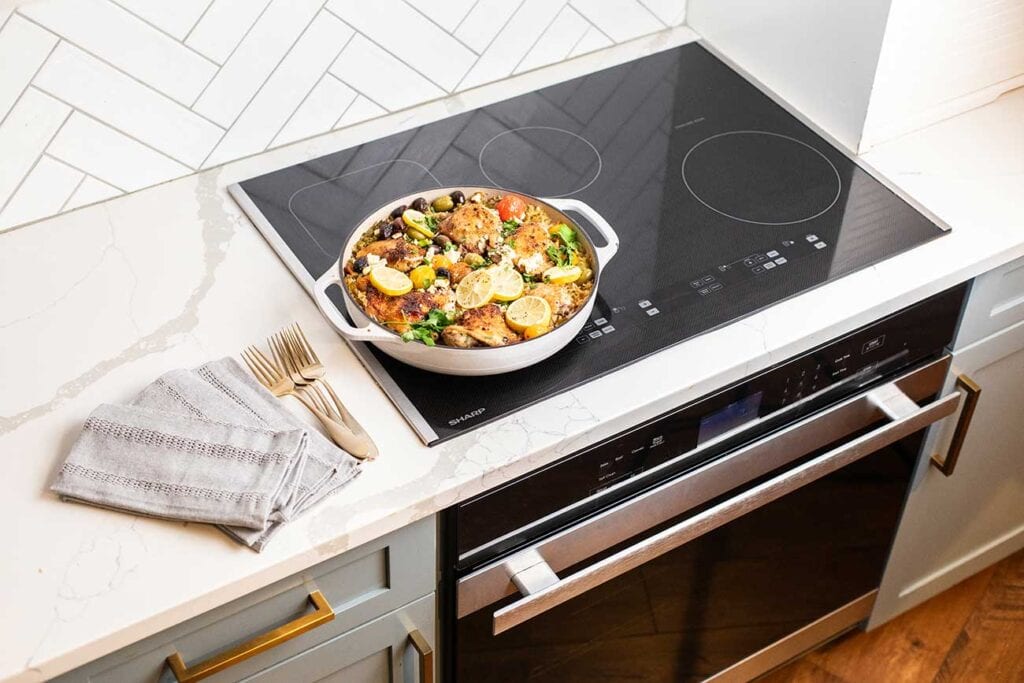 A cast iron braiser with rice and chicken sitting on the Sharp Induction Cooktop.