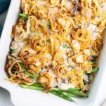 A close up look at a green bean casserole topped with lots of crispy shallots.