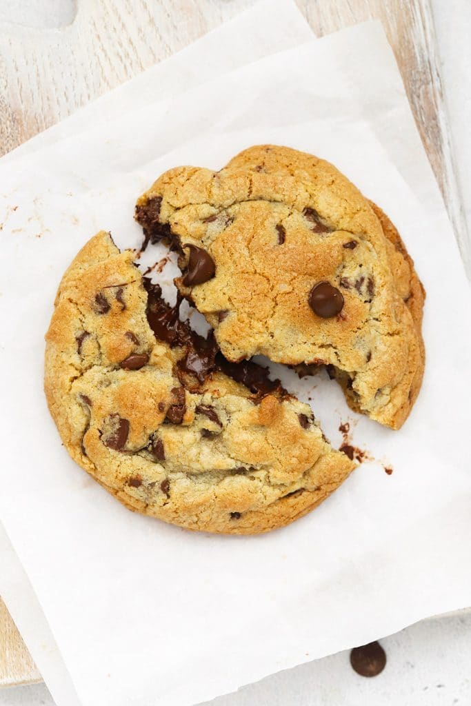 Breaking a gluten-free Levain chocolate chip cookie in half, revealing its gooey center