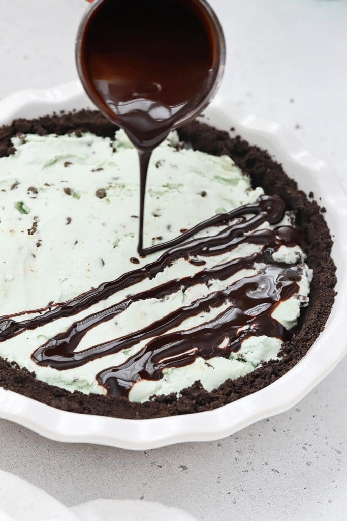 Drizzling chocolate sauce on gluten-free grasshopper pie