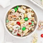 A white bowl of gluten-free christmas chex mix with m&ms and pretzels