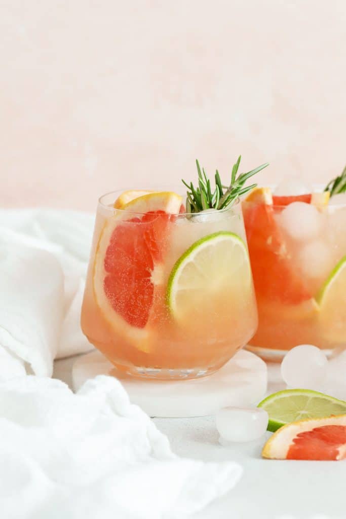 Two grapefruit mocktails garnished with grapefruit wedges, lime slices, and fresh rosemary