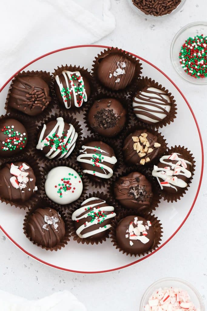 Gluten-free Oreo truffles decorated with different toppings on a white plate with a red rim