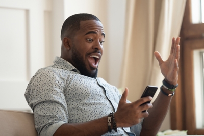 Surprised-man-holding-phone-on-sofa