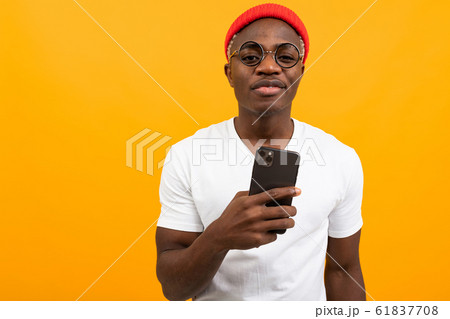 handsome african man in a white t-shirt communicates on a social network on a yellow studio 61837708