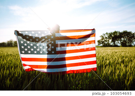 Man hold waving american USA flag. Patriot raise national american flag. Independence Day, 4th July. 103054693