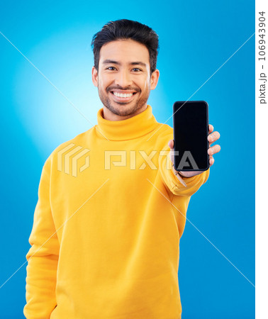 Advertising, portrait of man with smartphone and in blue background happy for social networking. Online communication, technology or marketing, branding and male person with cellphone app in studio 106943904