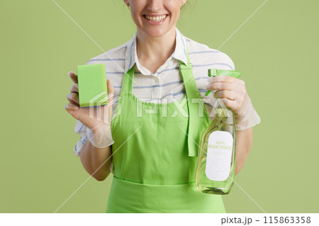 Smiling woman in green apron and rubber gloves isolated on green 115863358