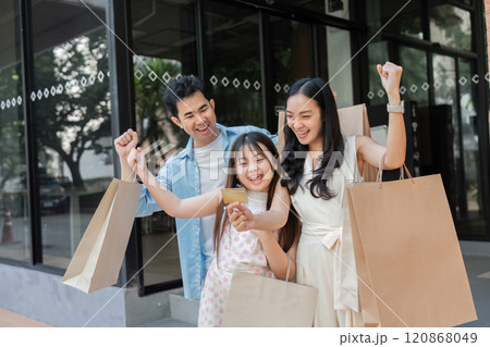 Happy Family Enjoying a Day of Shopping Together with Parents and Children Smiling and Holding Shopping Bags in a Modern Urban Setting 120868049