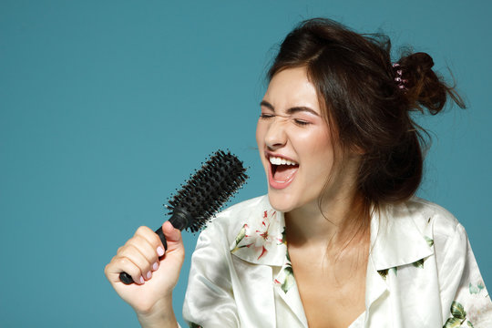 Cheerful attractive teen girl sing song holding comb like a micr