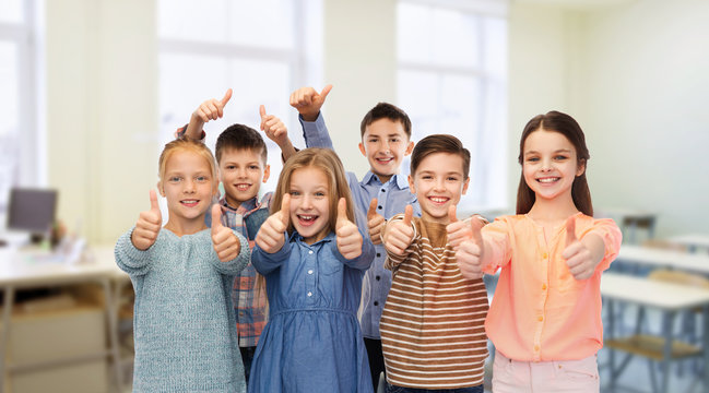 happy students showing thumbs up at school