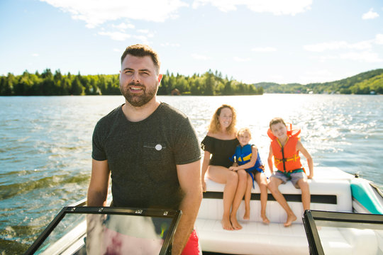 Man driving boat on holiday with his son kids and his wife