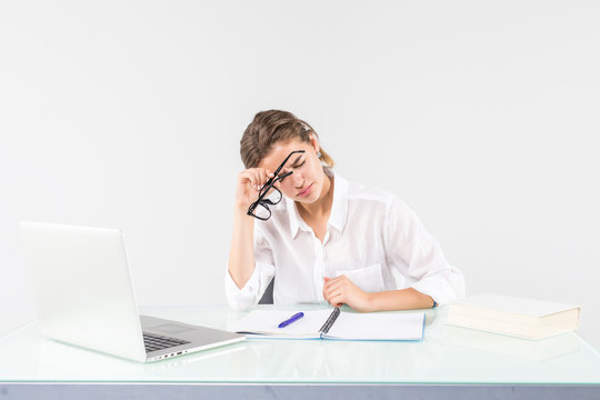 A businesswoman in front of laptop with a headache, sitting at the desk, isolated on white background