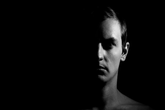 Dramatic portrait of a guy on a black background, black and white photography