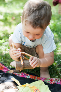 little boy plays with a wooden homemade constructor in the summer outside. Waldorf School