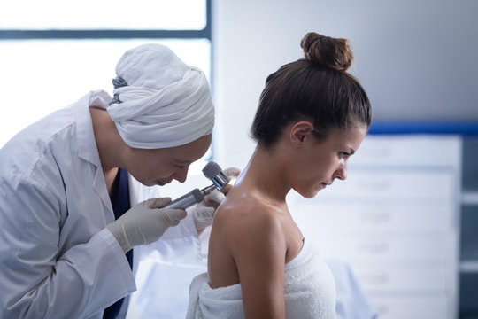 Female doctor checking patient with dermatoscopy